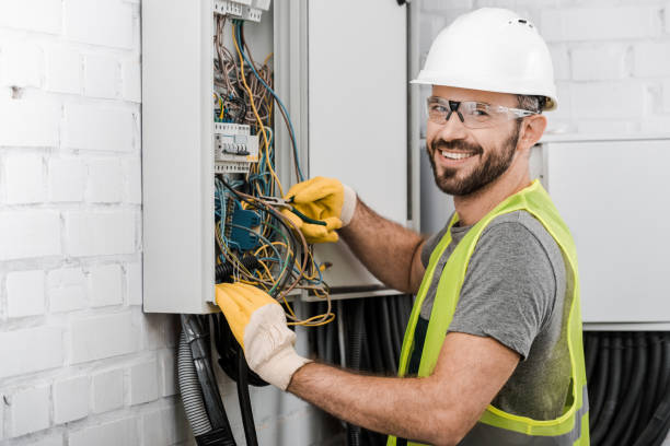 Electrician in a hard hat working on an electrical panel